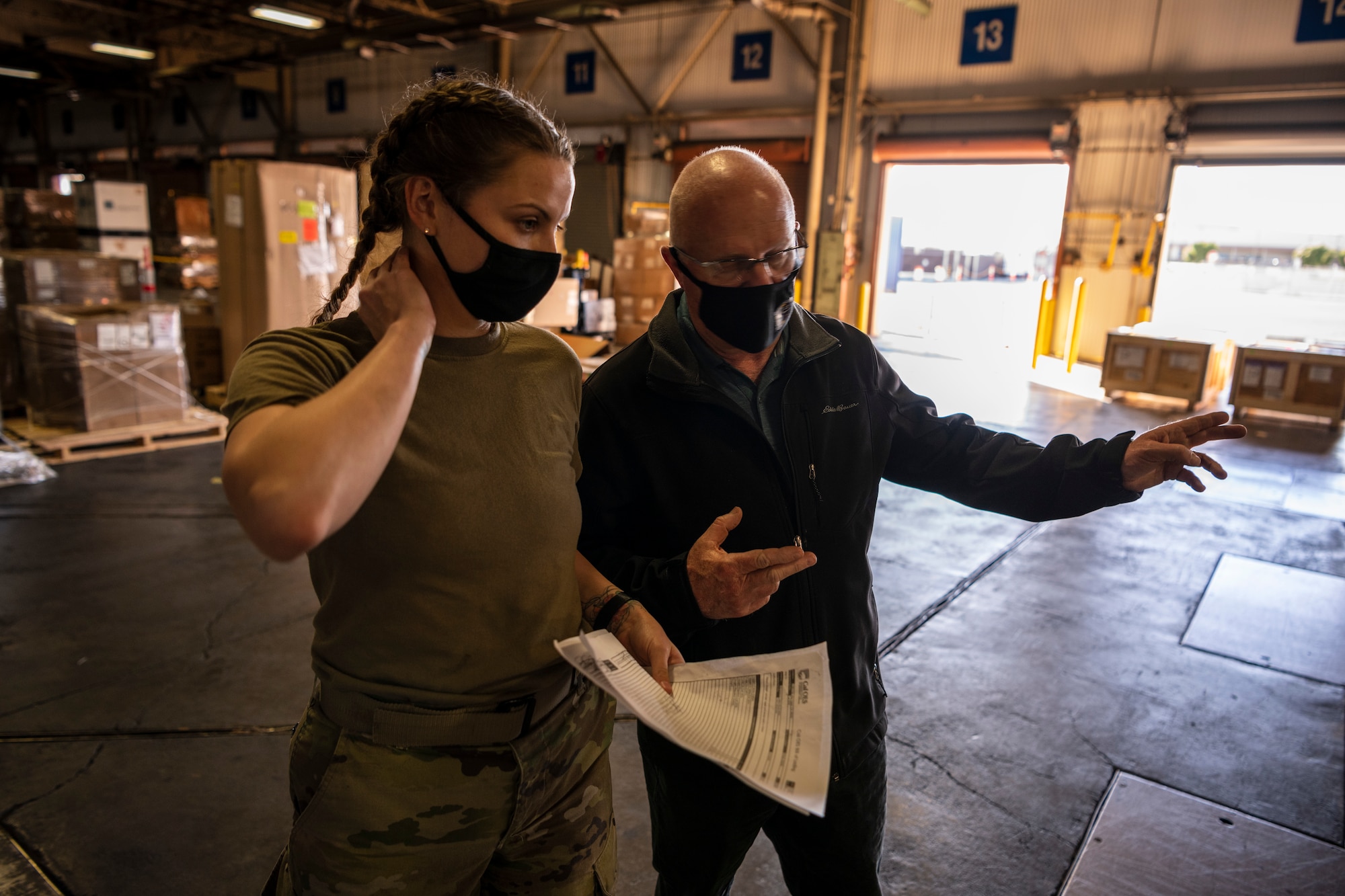 A woman and a man are seen talking in a large warehouse.