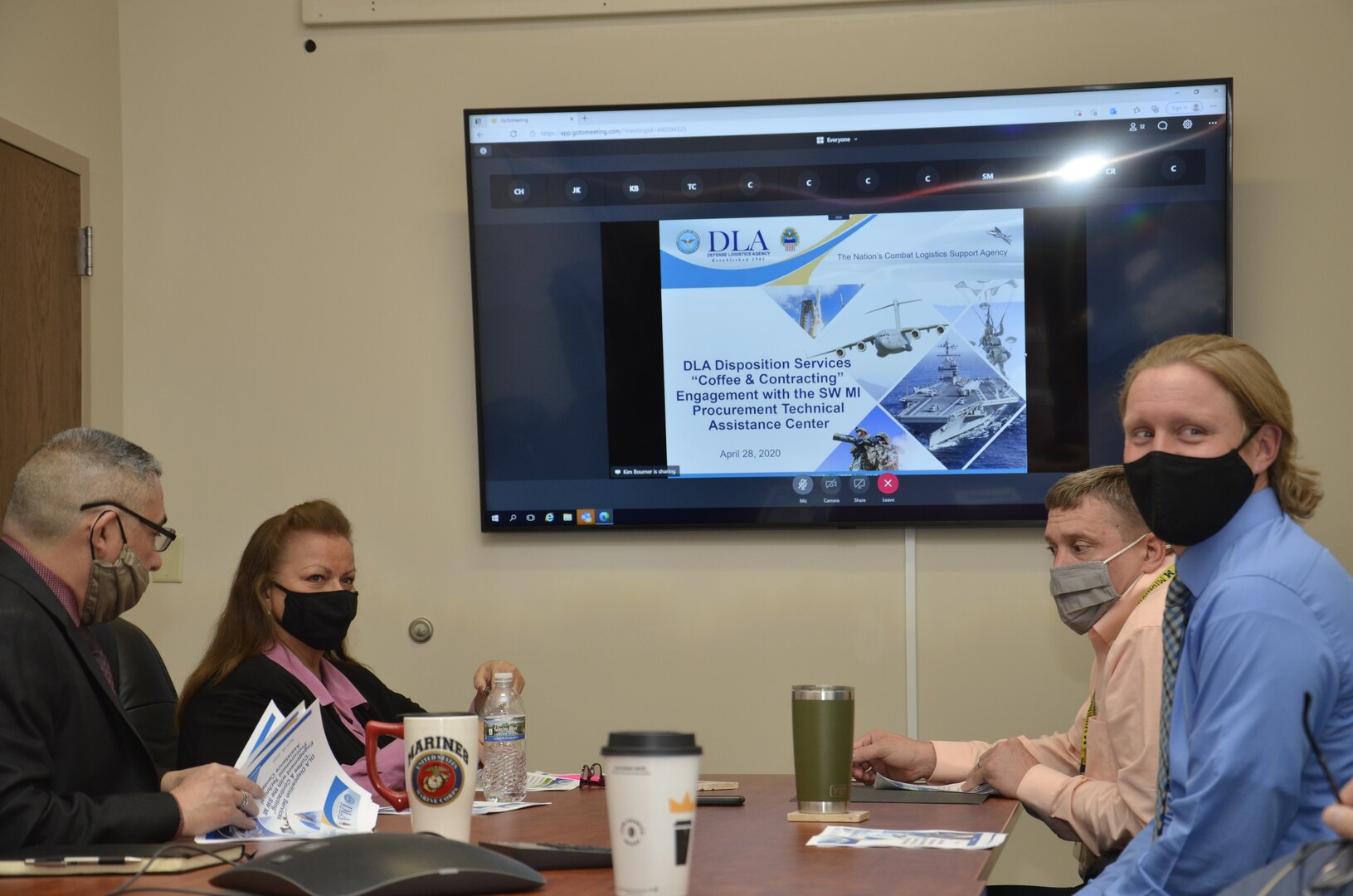 Four people sit at a conference room table briefing a telephone audience.