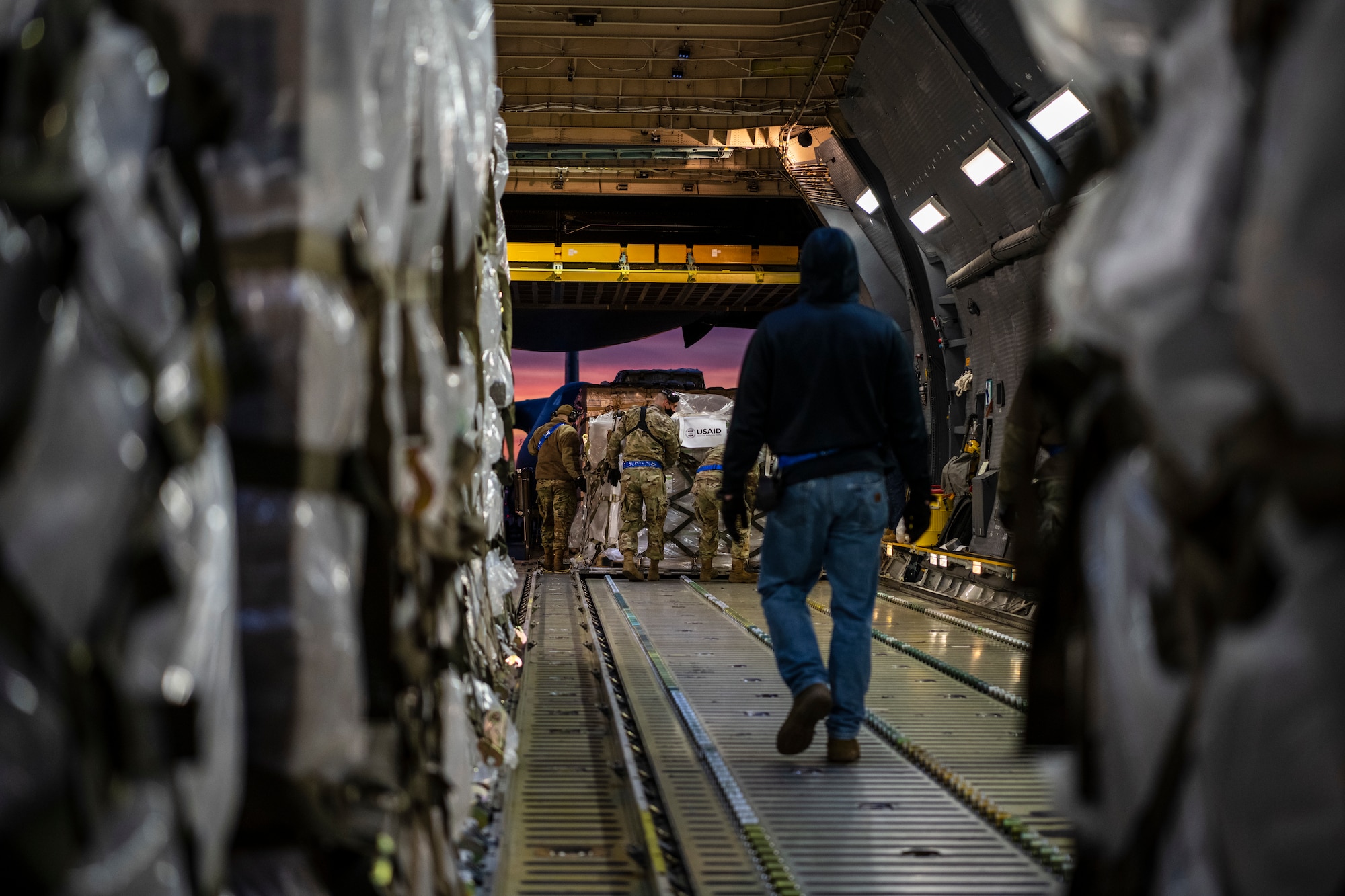 Airmen move pallets inside a large military aircraft.