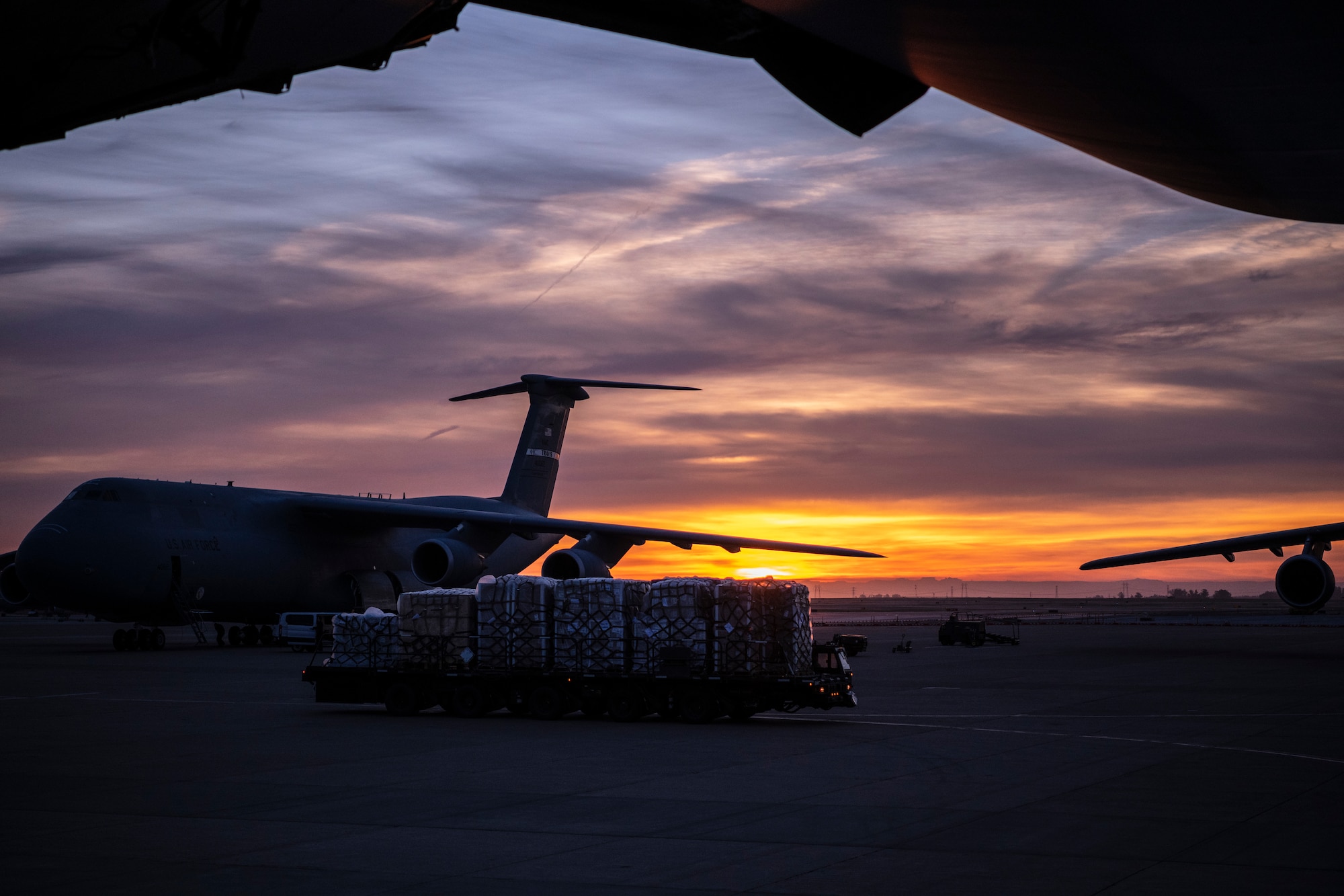 Airmen move pallets inside a large military aircraft.