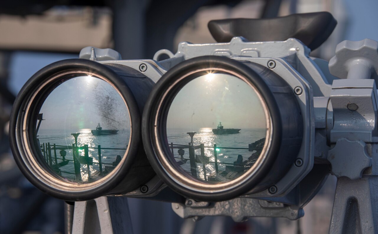 The reflection of a ship at sea shows on the lenses of a pair of binoculars.