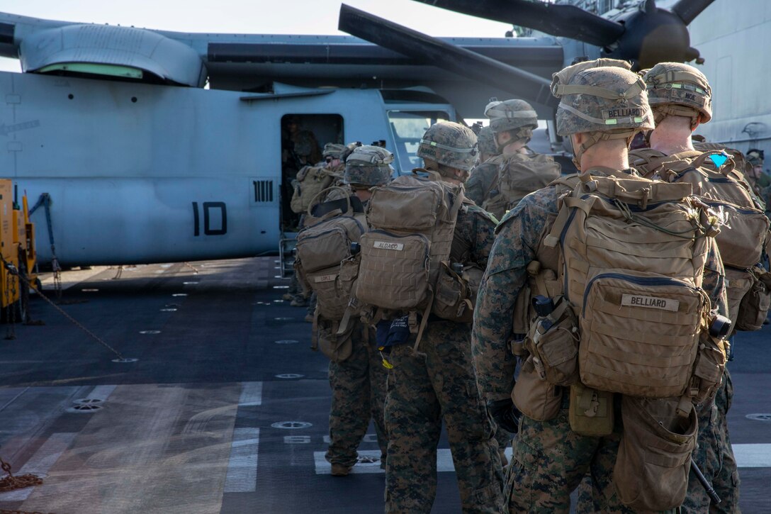 Marines file into a helicopter.