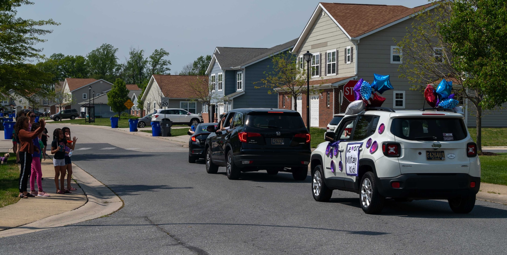 Children wave as teachers and faculty from George S. Welch Elementary and Dover Air Force Base Middle Schools drive through housing on Dover AFB, Delaware, during the Month of the Military Child parade April 28, 2021. The annual event is held each April as part of the month-long celebration of military children. (U.S. Air Force photo by Airman 1st Class Faith Schaefer)