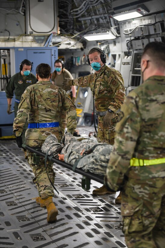 Senior Airman Nathan Boyer, 445th Aeromedical Evacuation Squadron, gives direction to Airmen transporting patients onto a 445th Airlift Wing C-17 Globemaster III during the Ultimate Caduceus training exercise April 29, 2021. U.S. Transportation Command (USTRANSCOM) began a week-long aeromedical and global patient movement exercise, Ultimate Caduceus, April 26. Approximately 250 personnel including members of the 445th Airlift Wing and the 88th Air Base Wing participated in the field training exercise. (U.S. Air Force photo//Master Sgt. Patrick O’Reilly)