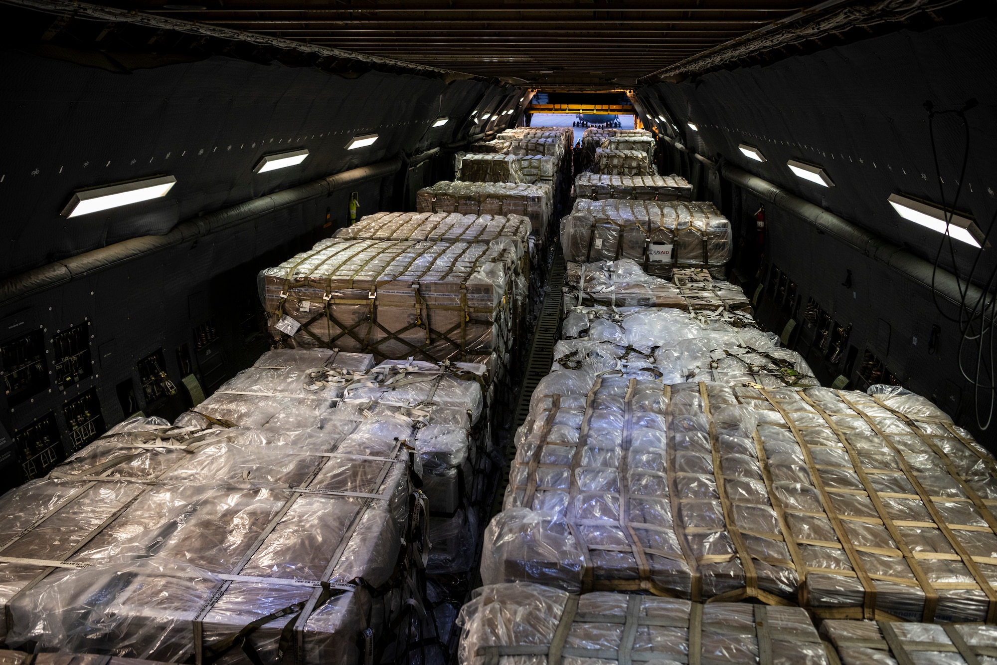 The inside view of an extremely large military aircraft full of pallets.