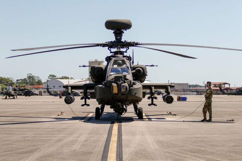 A man in a military uniform stands near a helicopter.