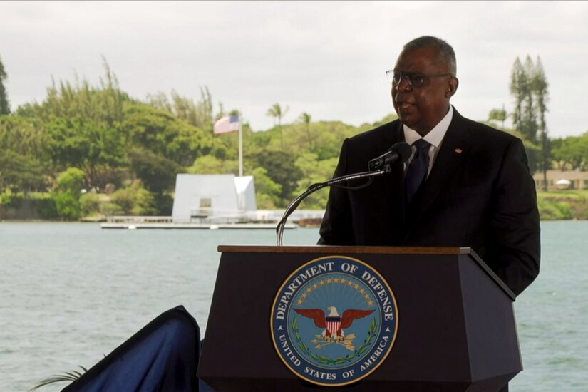 A man in a suit stands behind a lectern.