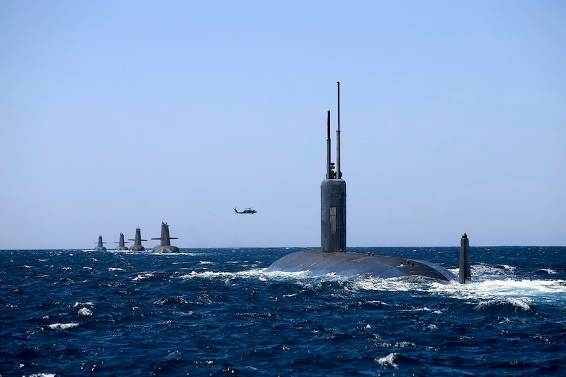 Multiple submarines move through the water together.
