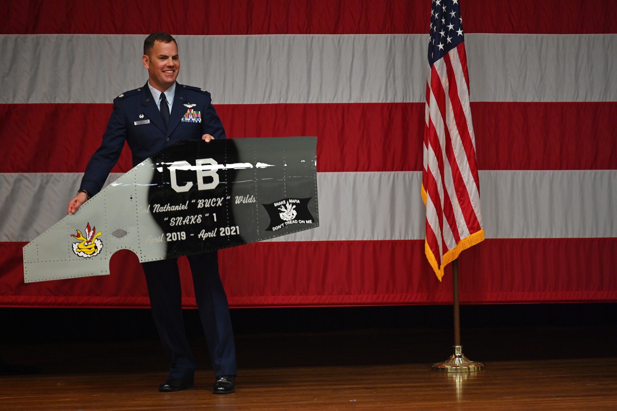 Lt. Col. Paul Anderson, 50th Flying Training Squadron commander, brings out a gift for the former 50th FTS commander at the 50th FTS change of command ceremony, April 30, 2021, on Columbus Air Force Base, Miss. Anderson assumed command of the 50th FTS from Lt. Col. Nathaniel Wilds. (U.S. Air Force photo by Senior Airman Jake Jacobsen)