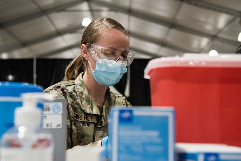 U.S. Air Force Senior Airman Daschia Lawrence, 92nd Healthcare Operation Squadron medical technician, prepares equipment for a COVID-19 vaccine April 27, 2021, at the Community Vaccination Center (CVC) in St. Paul, Minnesota. The total-force members include the U.S. Air Force, U.S. Army and U.S. Coast Guard from 24 bases across the country supporting the CVC. (U.S. Air Force photo by Senior Airman Alexi Bosarge)