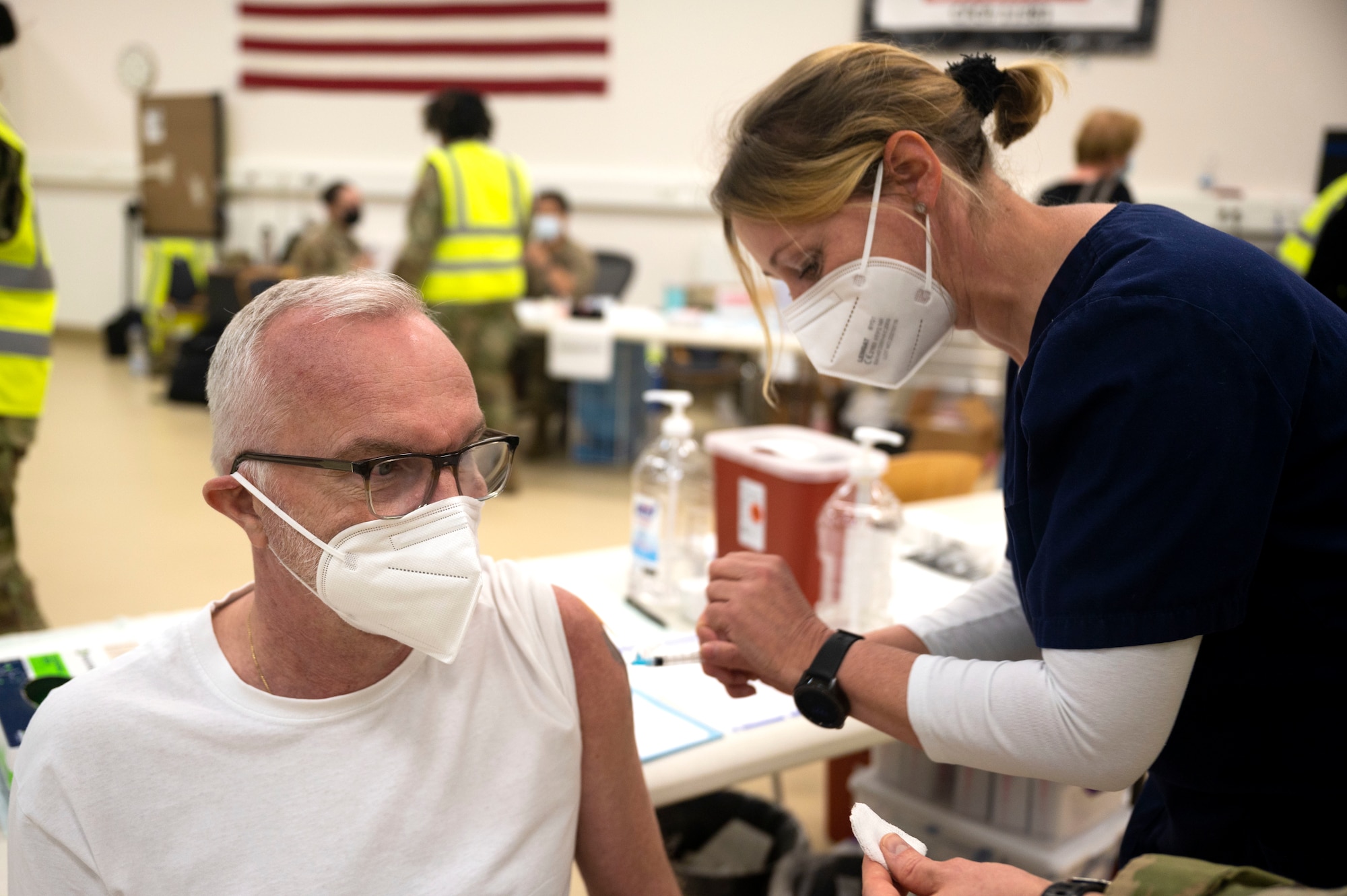 Andreas Heinze, 721st Aerial Port Squadron motor carrier safety specialist, receives a COVID-19 vaccine shot from Iris Geist, a German local national nurse, at Ramstein Air Base, Germany