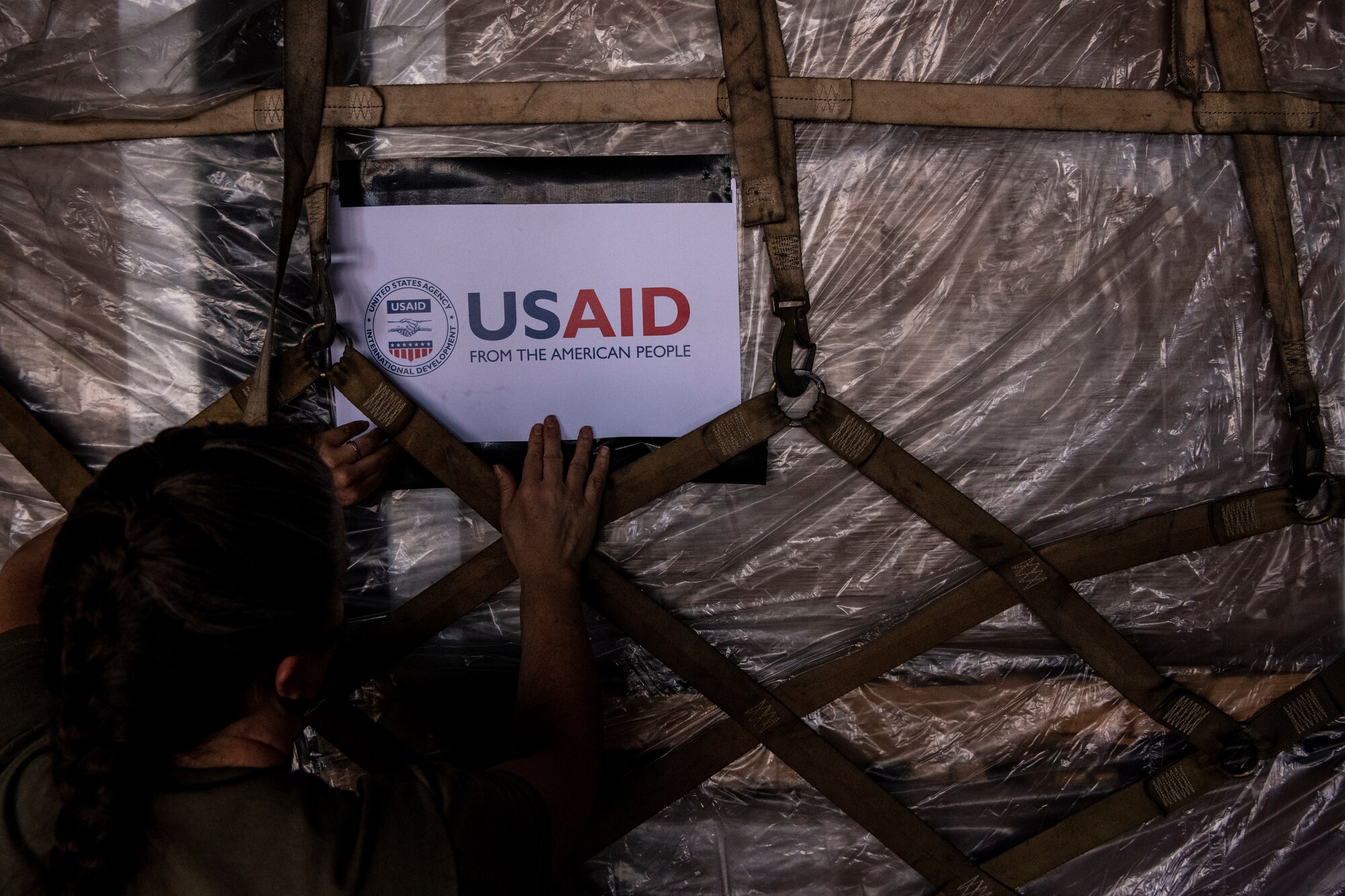 A sign is being placed on a pallet and the sign says "USAID, from the American people."