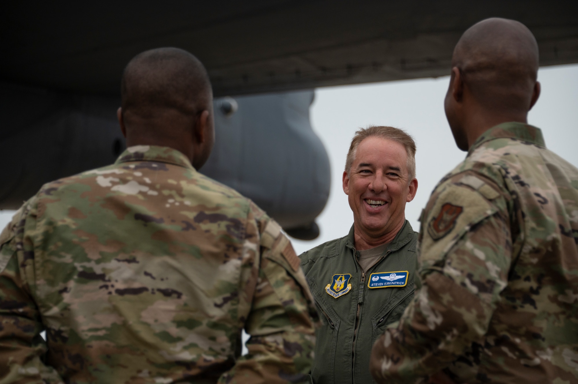 man smiles at two other men