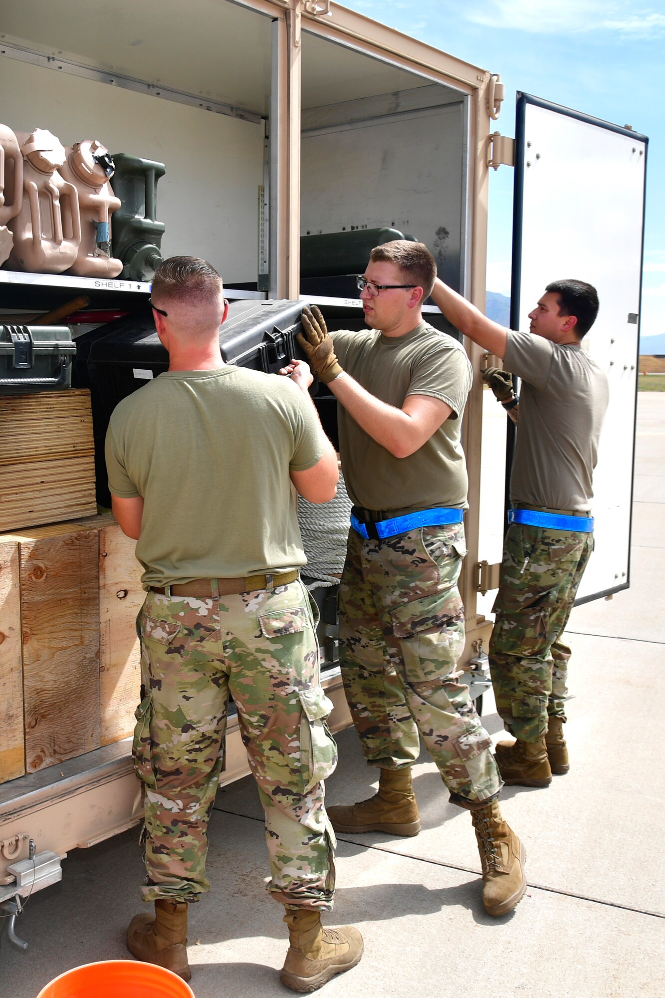 Airmen loading a container box sitting on a pallet.