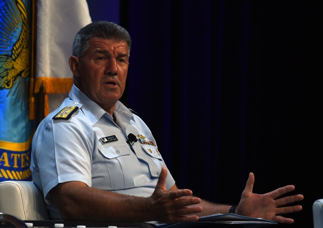 A man in uniform speaks while making a gesture with his hands to emphasize what he's saying.