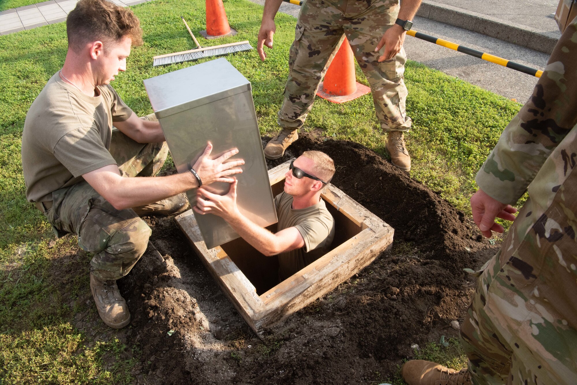 Airmen place a time capsule into a hole.