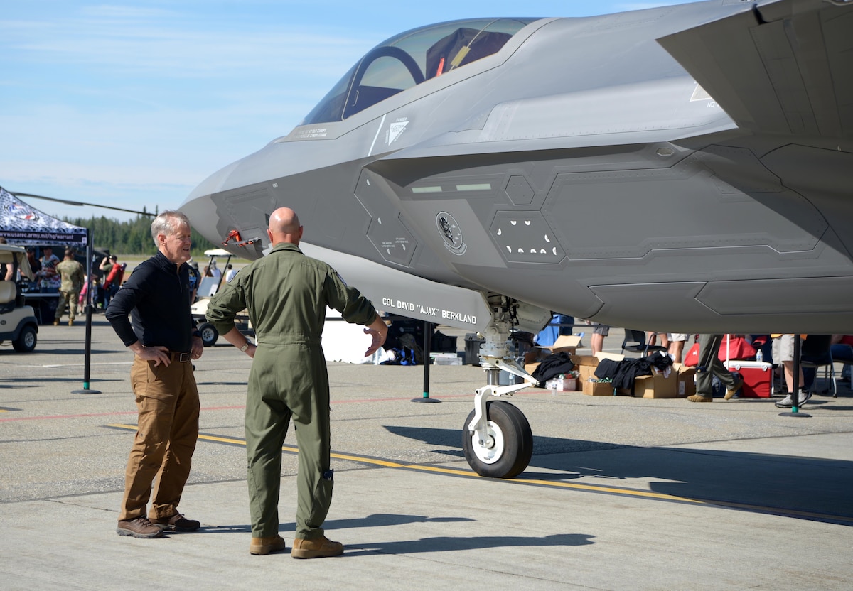 Two men stand near an F-35A Lightning II aircraft.