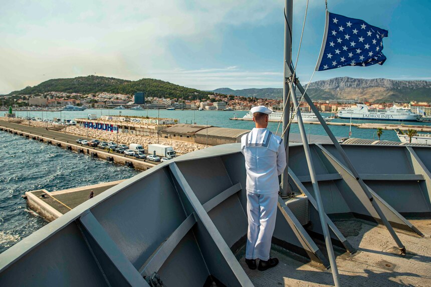Hospital Corpsman 2nd Class Donald Coony lowers the ships Jack   aboard the Blue Ridge-class command and control ship USS Mount Whitney (LCC 20) as the ship gets underway from Split, Croatia, August 2, 2021. Mount Whitney is the U.S. Sixth Fleet flagship, homeported in Gaeta, and operates with a combined crew of U.S. Sailors and Military Sealift Command civil service mariners.