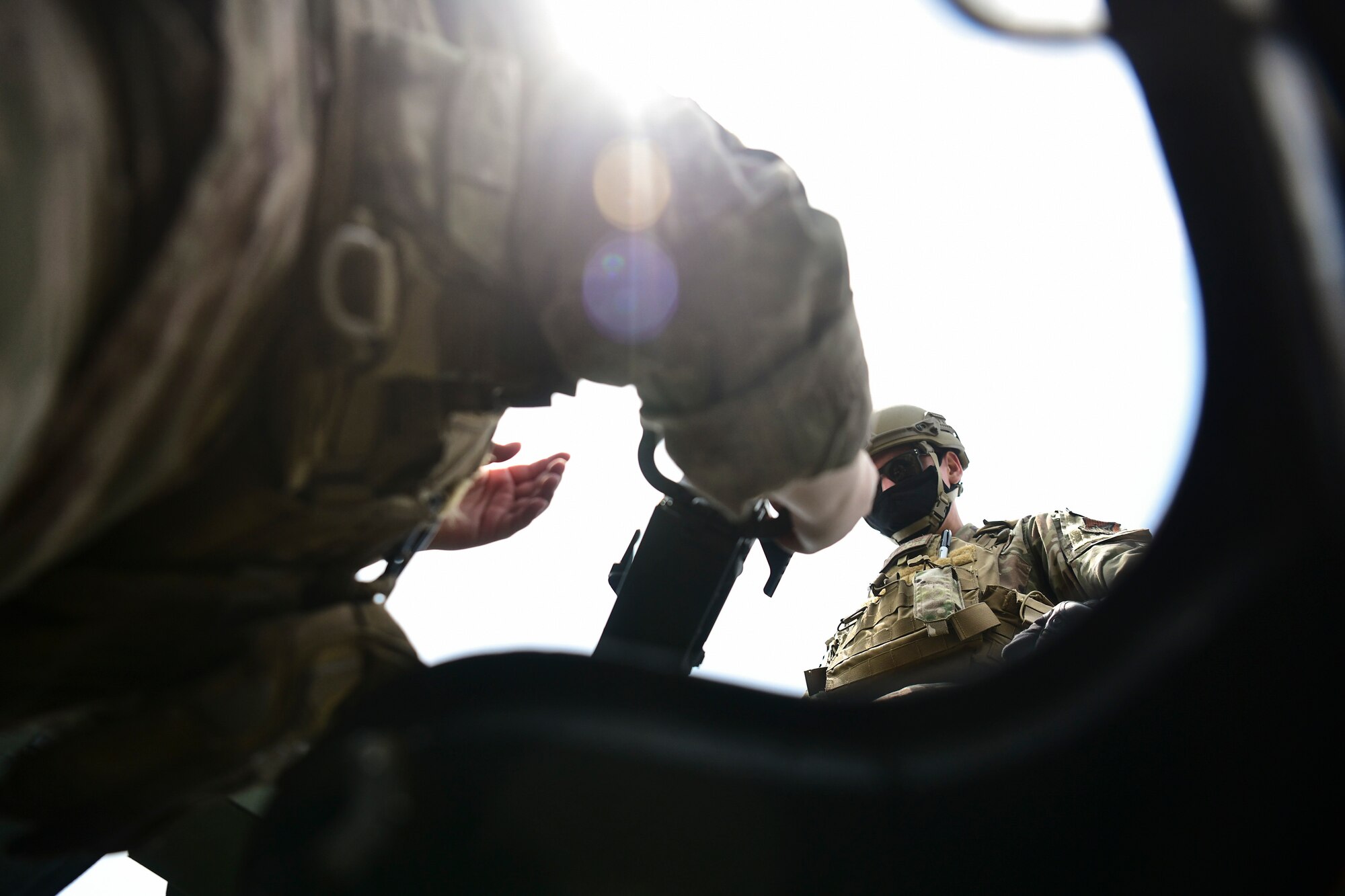 Airmen place a machine gun onto a Humvee.