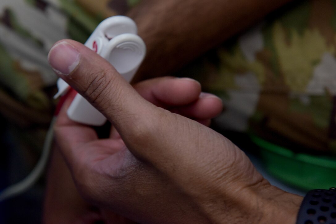 U.S. Air Force Airman simulates taking someone's vitals during a scenario for Negatively Pressurized Conex Lite training