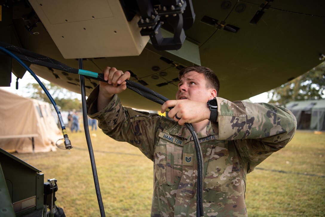 A U.S. service member wires a communications satellite.