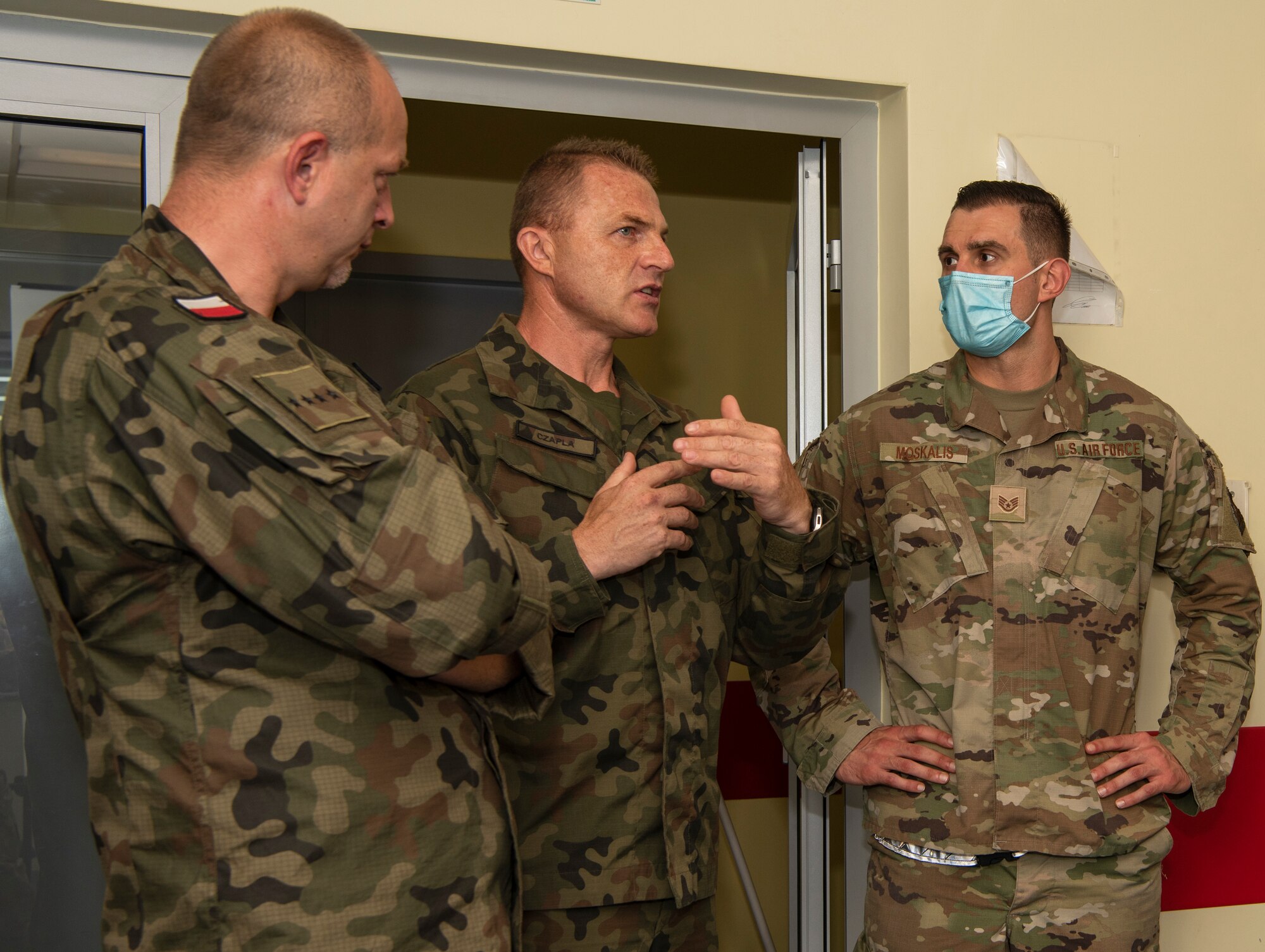 Warrant Officer Mariusz Galka, fire chief, 32nd Tactical Air Base (center), and Warrant Officer Adam Czapla, deputy fire chief, 32nd Tactical Air Base and U.S. Air Force Staff Sgt. Bernard Moskalis (right), non-destructive inspection craftsman, 480th Expeditionary Fighter Squadron, discuss emergency response with two dozen emergency responders at Łask Air Base, Poland, July 28, 2021. The meeting was in preparation of Aviation Detachment Rotation 21.3 and was designed to eliminate any confusion that could arise between U.S. service members and Polish firefighters during the exercise. (U.S. Air Force photo by Tech. Sgt. Anthony Plyler)