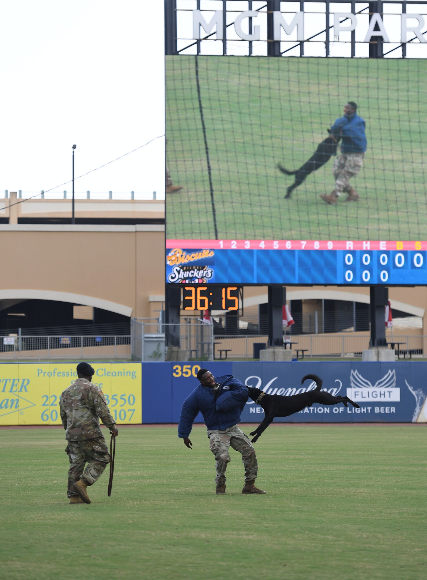 U.S. Air Force Tech. Sgt. LaQuan Conner, 81st Security Forces Squadron military working dog kennel master, Staff Sgt. Victor Henderson, 81st SFS military working dog handler, and Bbasso, 81st SFS military working dog, participate in a demonstration at the MGM Park during a Biloxi Shuckers Minor League Baseball team pre-game festivities in Biloxi, Mississippi, Aug. 1, 2021. The "Bark in the Park" themed baseball game invited fans to attend the game with their dogs. (U.S. Air Force photo by Kemberly Groue)