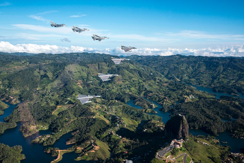 Jets fly in a V formation over mountainous terrain.