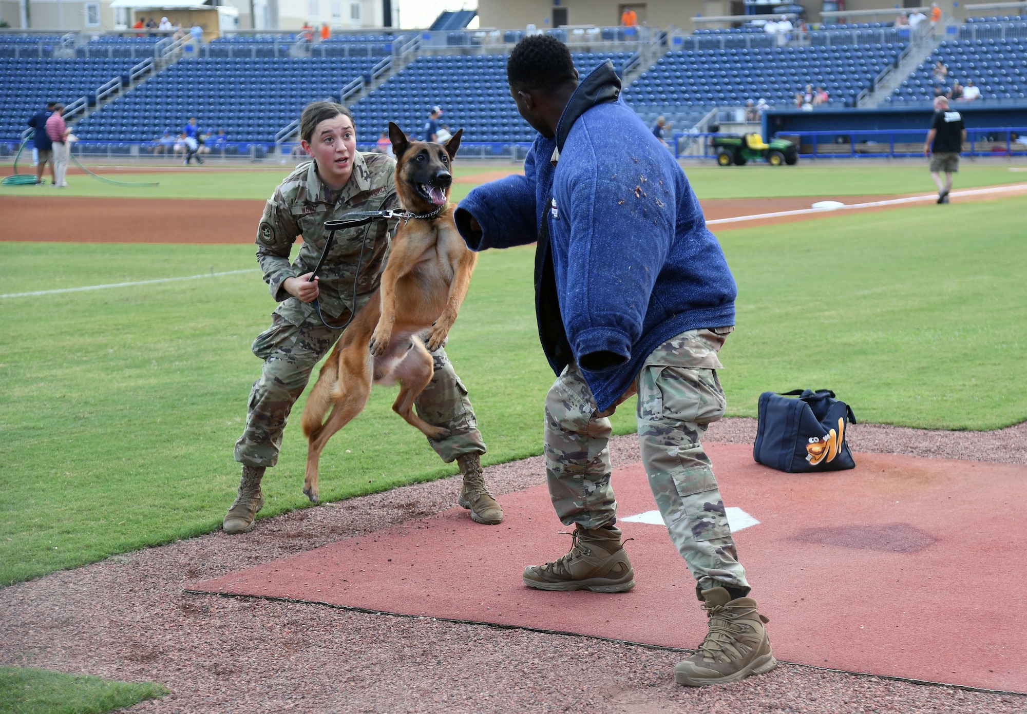 U.S. Air Force Senior Airman Ryan Wood and Staff Sgt. Victor Henderson, 81st Security Forces Squadron military working dog handlers, and Victor, 81st SFS military working dog, participate in a demonstration at the MGM Park during a Biloxi Shuckers Minor League Baseball team pre-game festivities in Biloxi, Mississippi, Aug.1, 2021. The "Bark in the Park" themed baseball game invited fans to attend the game with their dogs. (U.S. Air Force photo by Kemberly Groue)