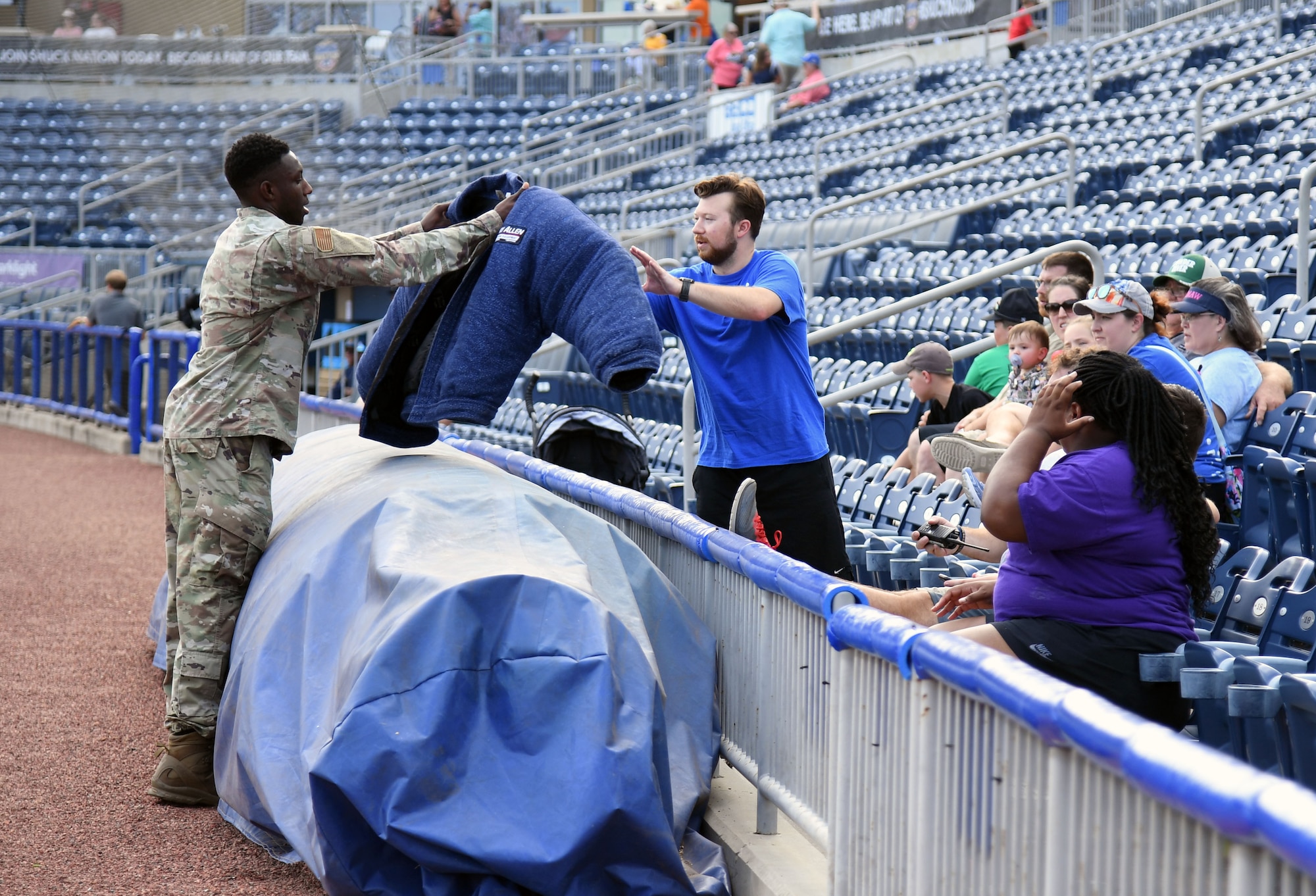 U.S. Air Force Staff Sgt. Victor Henderson, 81st Security Forces Squadron military working dog handler, shows attendees a bite suit following a military working dog demonstration at the MGM Park during a Biloxi Shuckers Minor League Baseball team pre-game festivities in Biloxi, Mississippi, Aug. 1, 2021. The "Bark in the Park" themed baseball game invited fans to attend the game with their dogs. (U.S. Air Force photo by Kemberly Groue)