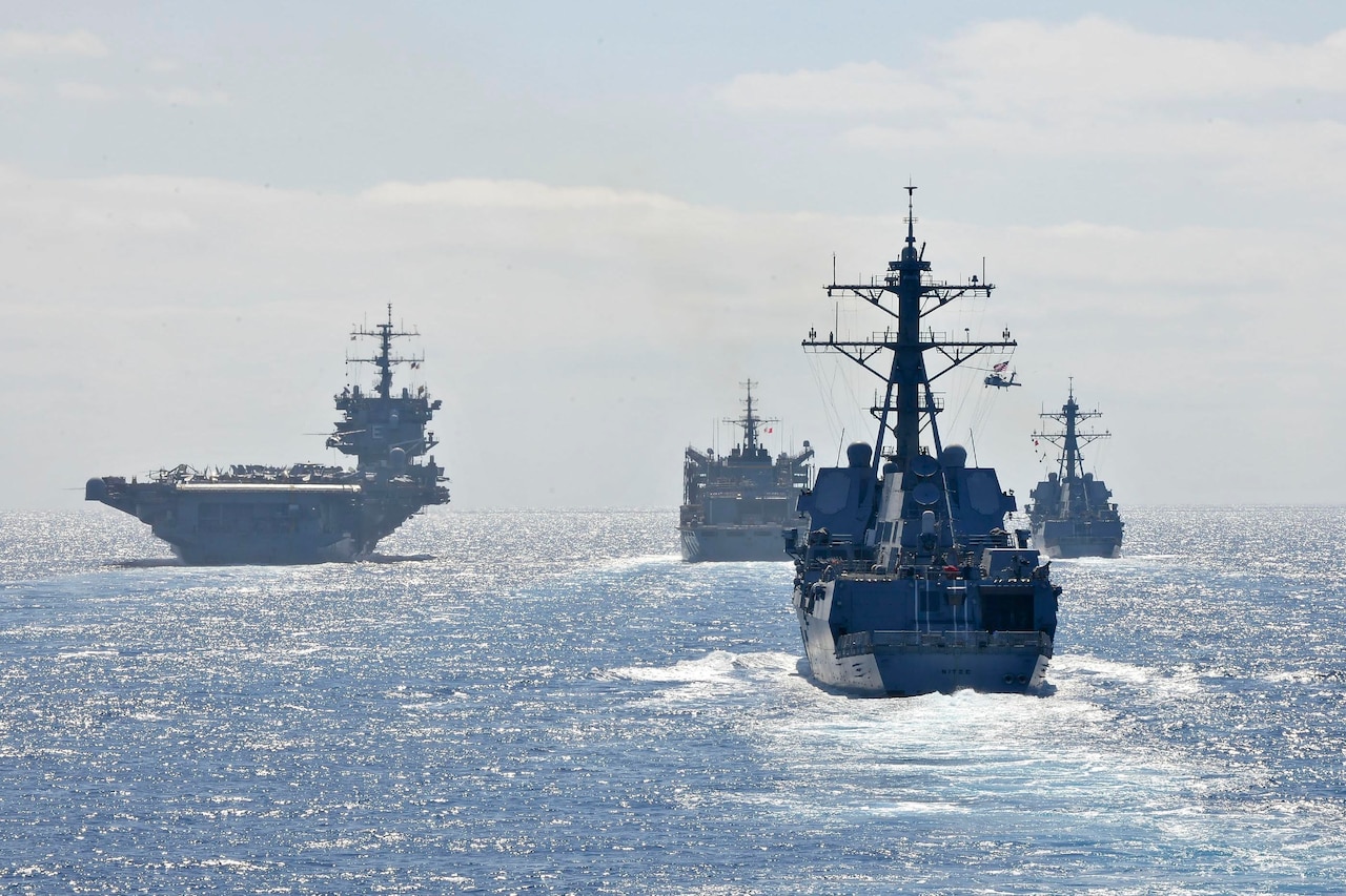 Military ships move together through the ocean.