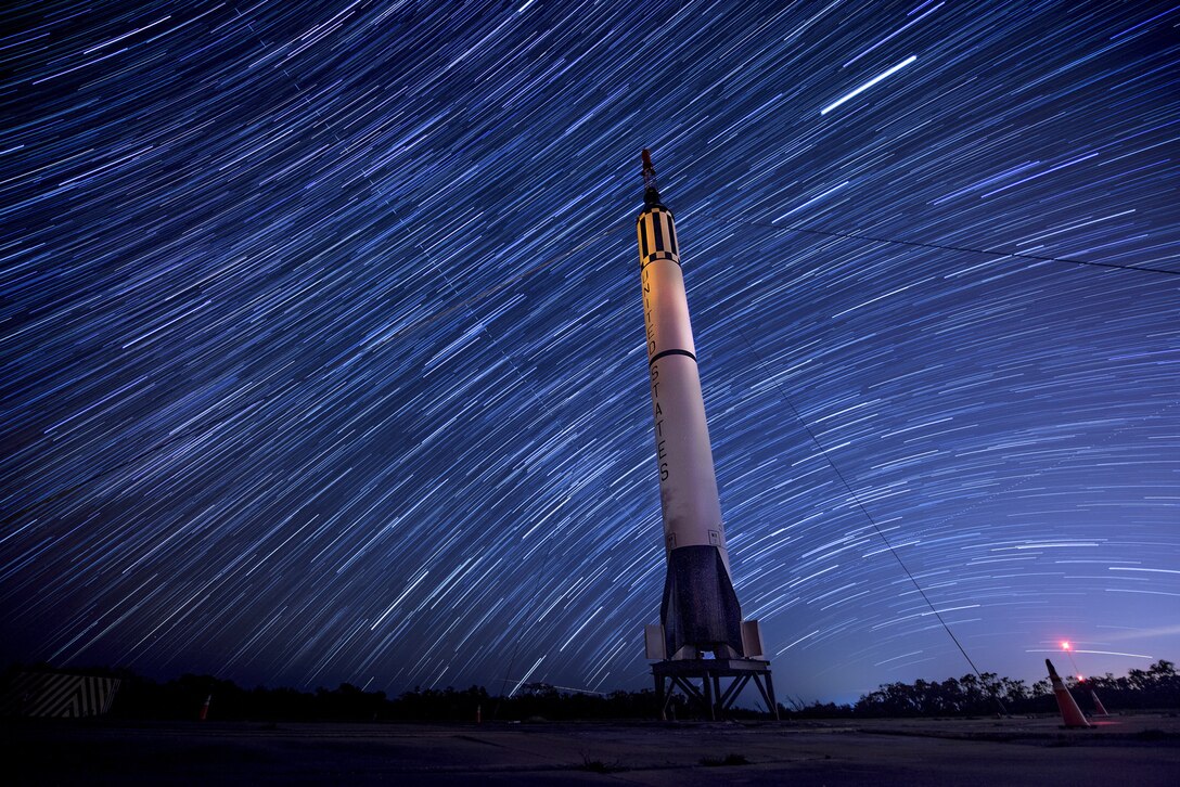 Stars move through a night sky.  A rocket is on display.