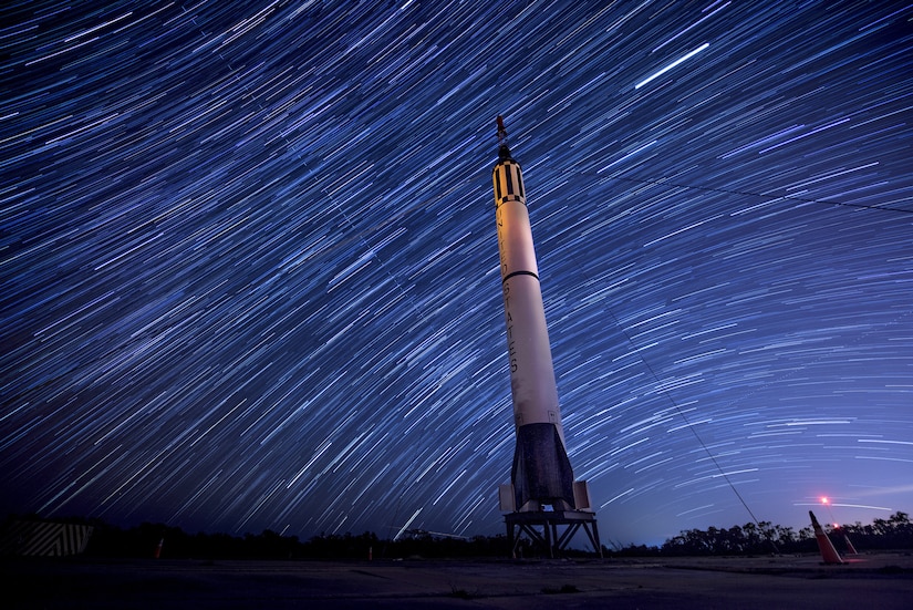 Stars move through a night sky.  A rocket is on display.