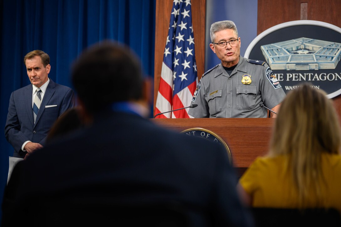 A man in a police uniform speaks with members of the press.