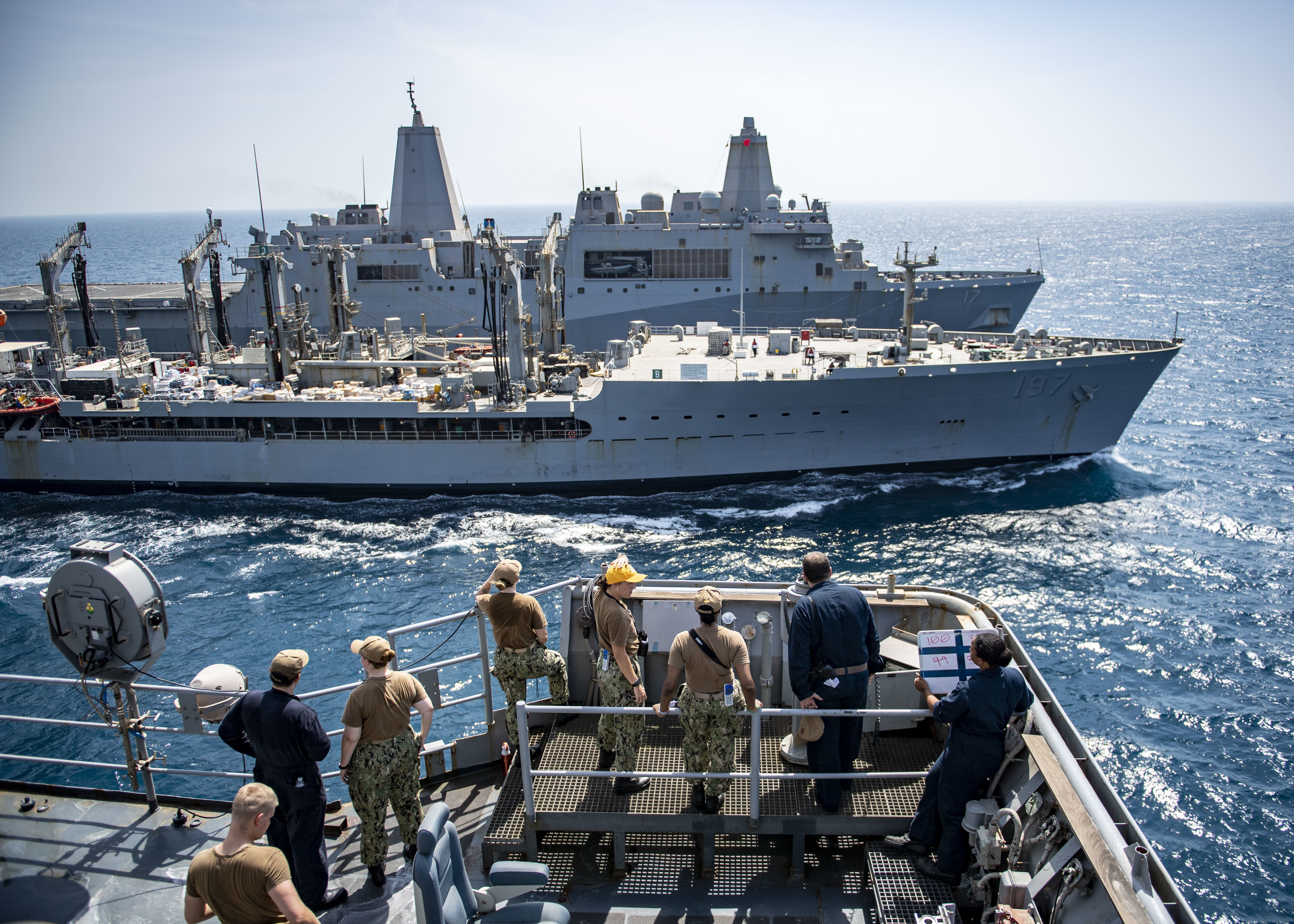 Sailors assigned to the dock landing ship USS Carter Hall (LSD 50) observe a replenishment-at-sea between the amphibious transport dock ship USS San Antonio (LPD 17), back, and the fleet replenishment oiler USNS Pecos (T-AO 197), middle.