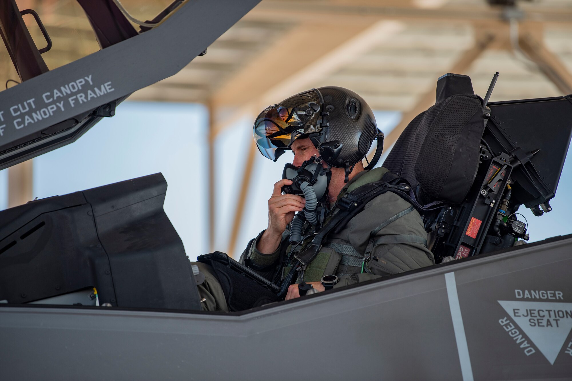 crew chief with hands in air with wrists crossed to the side of an F-35 on the flight line