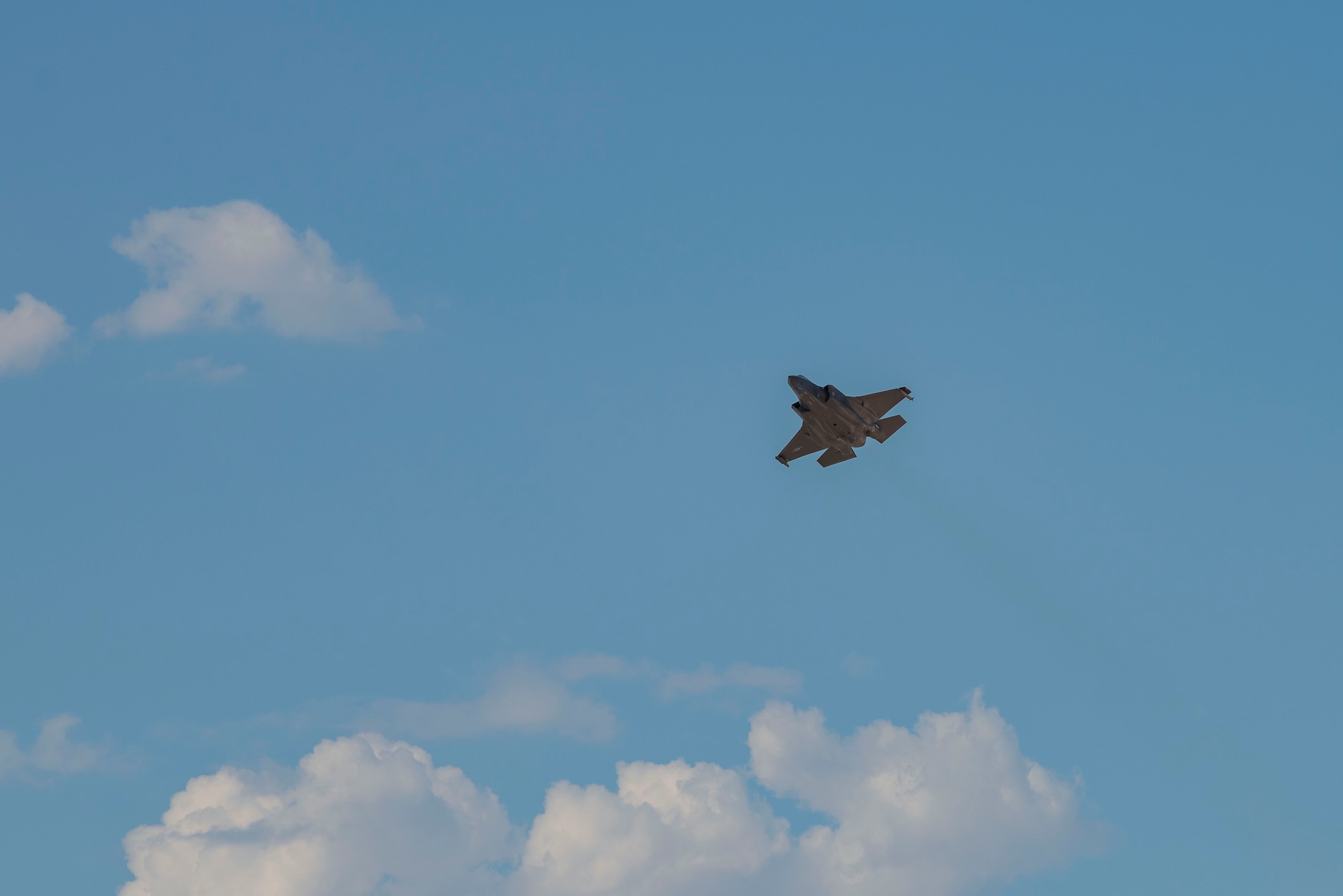 crew chief with hands in air with wrists crossed to the side of an F-35 on the flight line