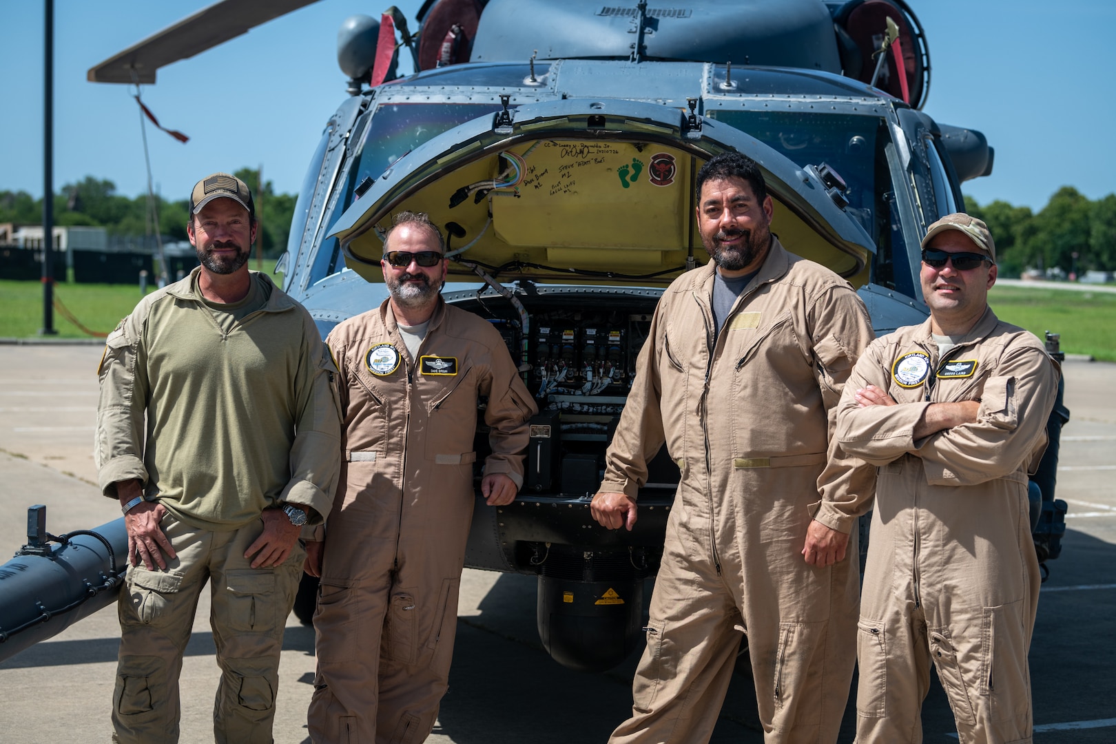 Crew stands in front of helicopter they've delivered.