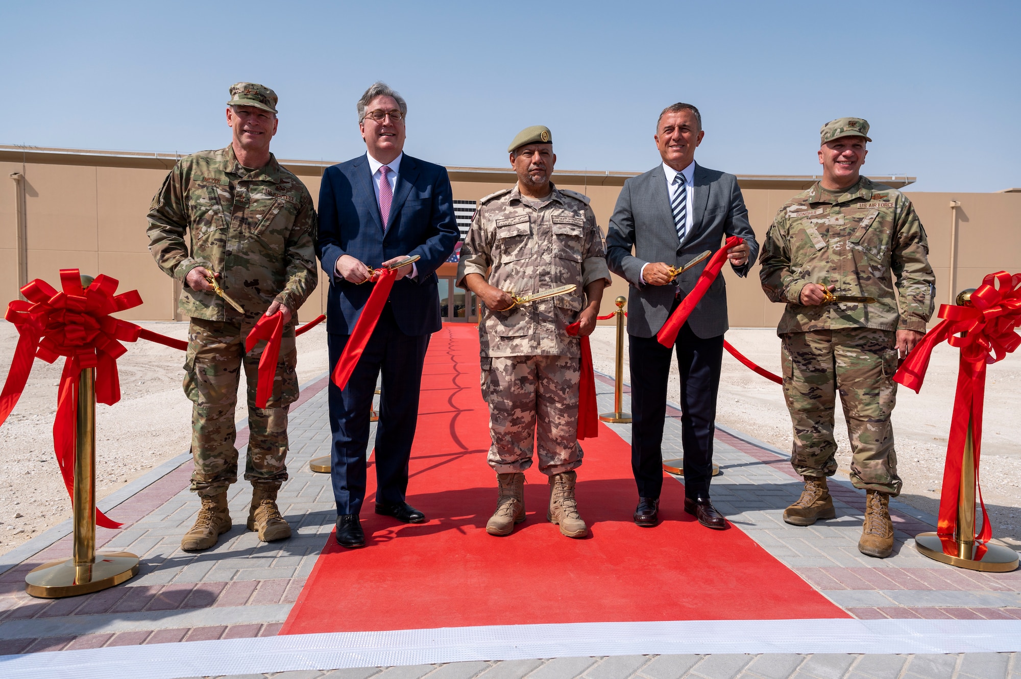Distinguished guests from the U.S. Embassy in Qatar, Qatar Emiri Corps of Engineers, U.S. Air Forces Central and Bahadir Construction Engineering Contracting and Trading Company cut the ribbon outside the new Blatchford-Preston Complex dormitory Aug. 3, 2021, at Al Udeid Air Base, Qatar.