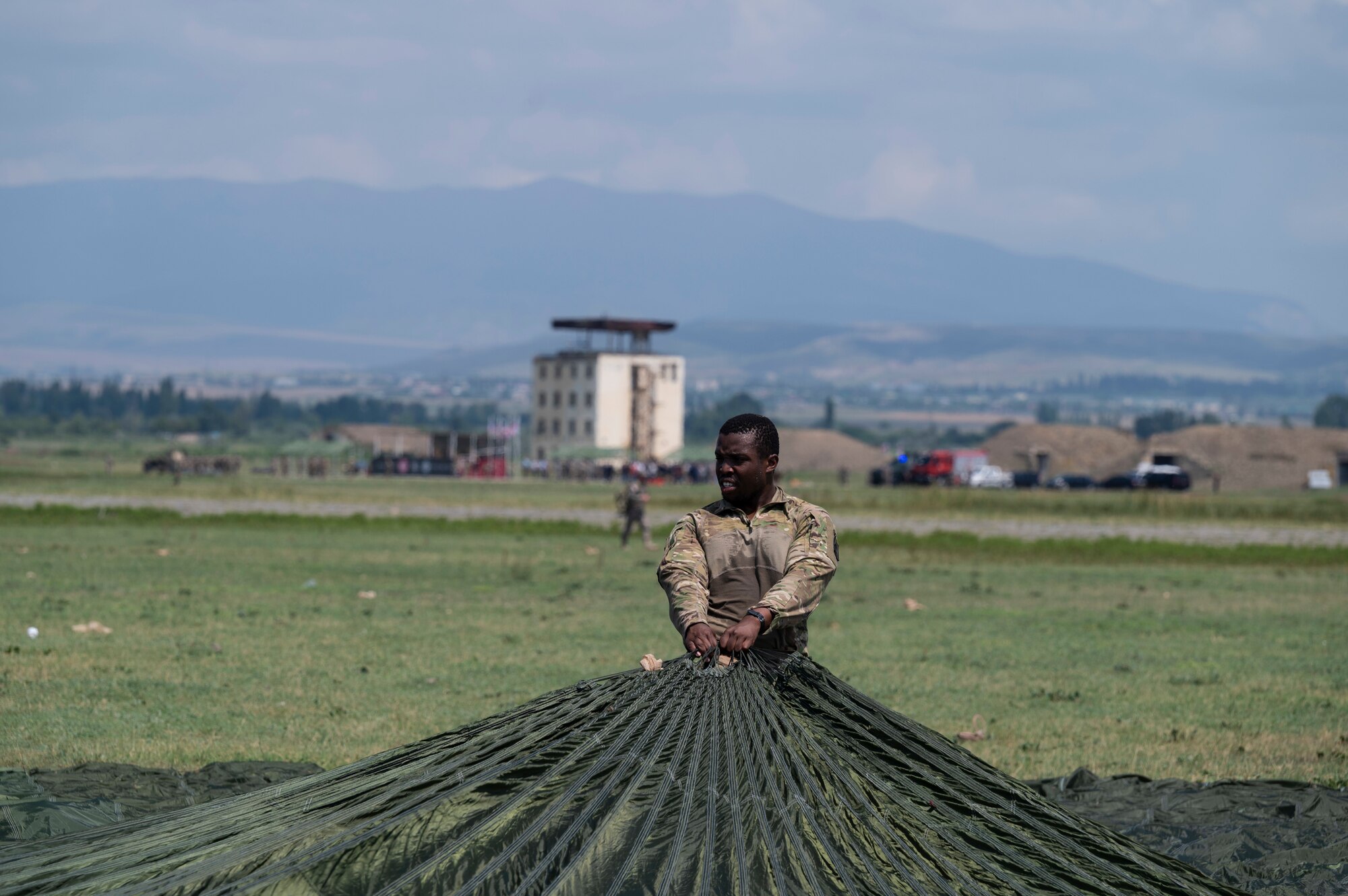 U.S. Army Private First Class Miles Farley, 1st Squadron, 91st Cavalry Regiment, 173rd Infantry Brigade Combat Team (airborne) cavalry scout, retrieves a parachute from the dropzone during exercise Agile Spirit 21