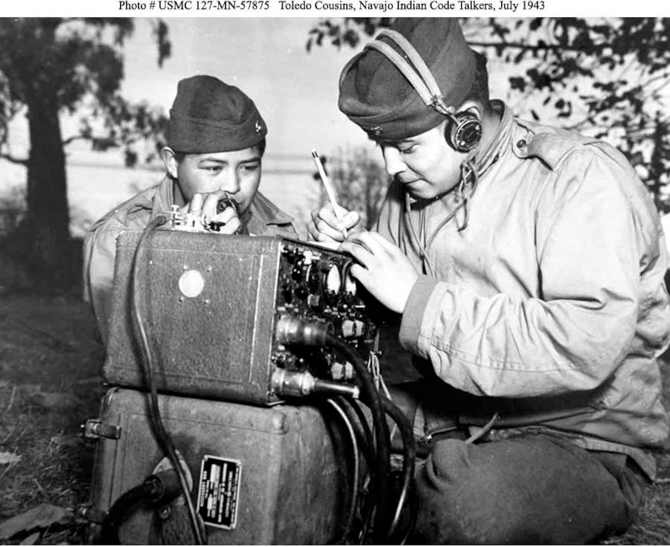 Marine Pfcs. Preston Toledo and Frank Toledo, both Navajo Code Talkers and cousins, relay orders in the Navajo language on a field radio. They were attached to a Marine artillery regiment in the South Pacific. This photo was taken July 7, 1943.