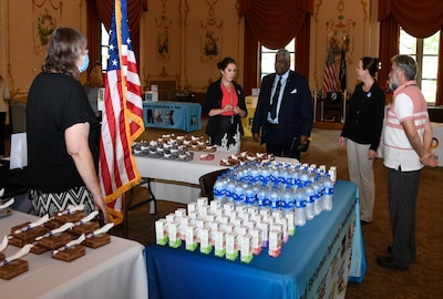 Man and women standing around a table looking at individually packaged pies and beverages.