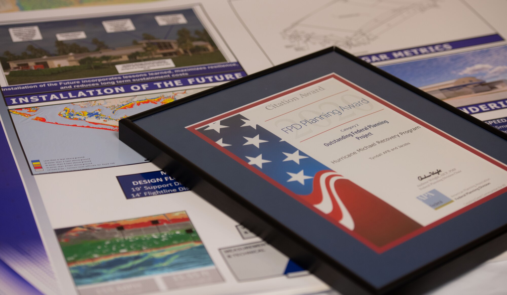 An award certificate lays on top of base plans