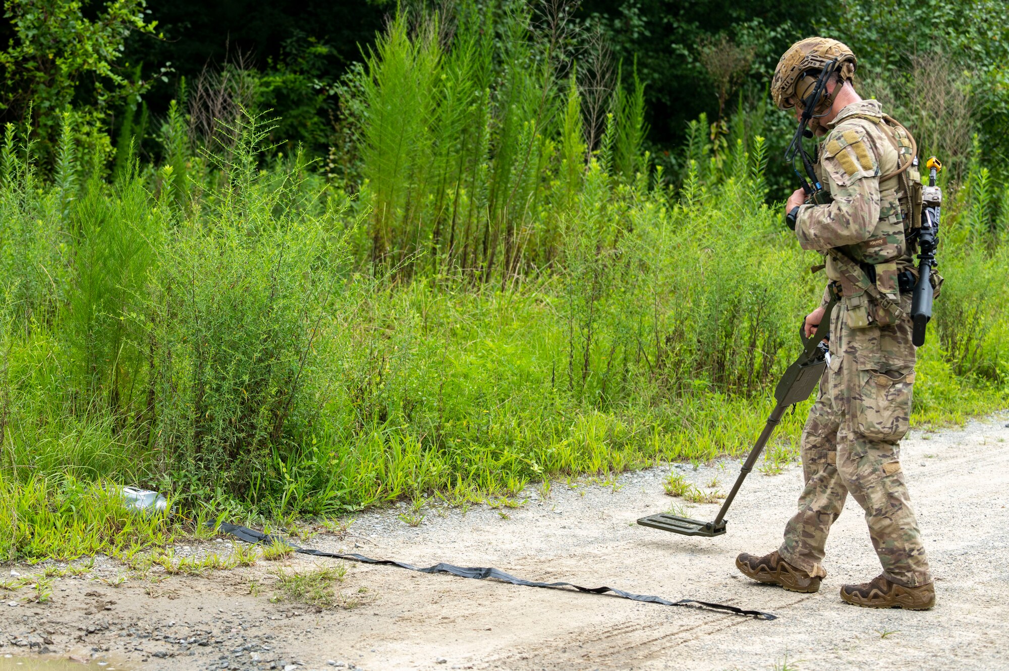 Senior Airman Joseph Plato, 4th Civil Engineer Squadron explosive ordnance disposal technician, uses a digital hand-held metal detector as he approaches a training roadside improvised explosive device during field training exercise Operation Guillotine at Seymour Johnson Air Force Base, North Carolina, July 27, 2021.