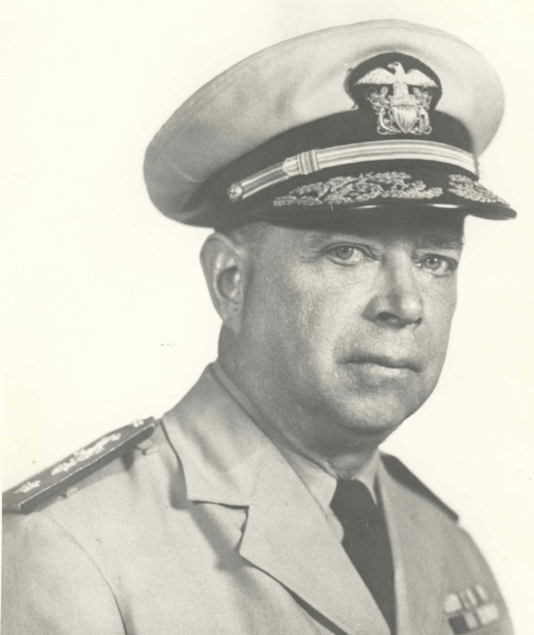 An older man wearing a Navy cap and dress shirt poses for a photo.