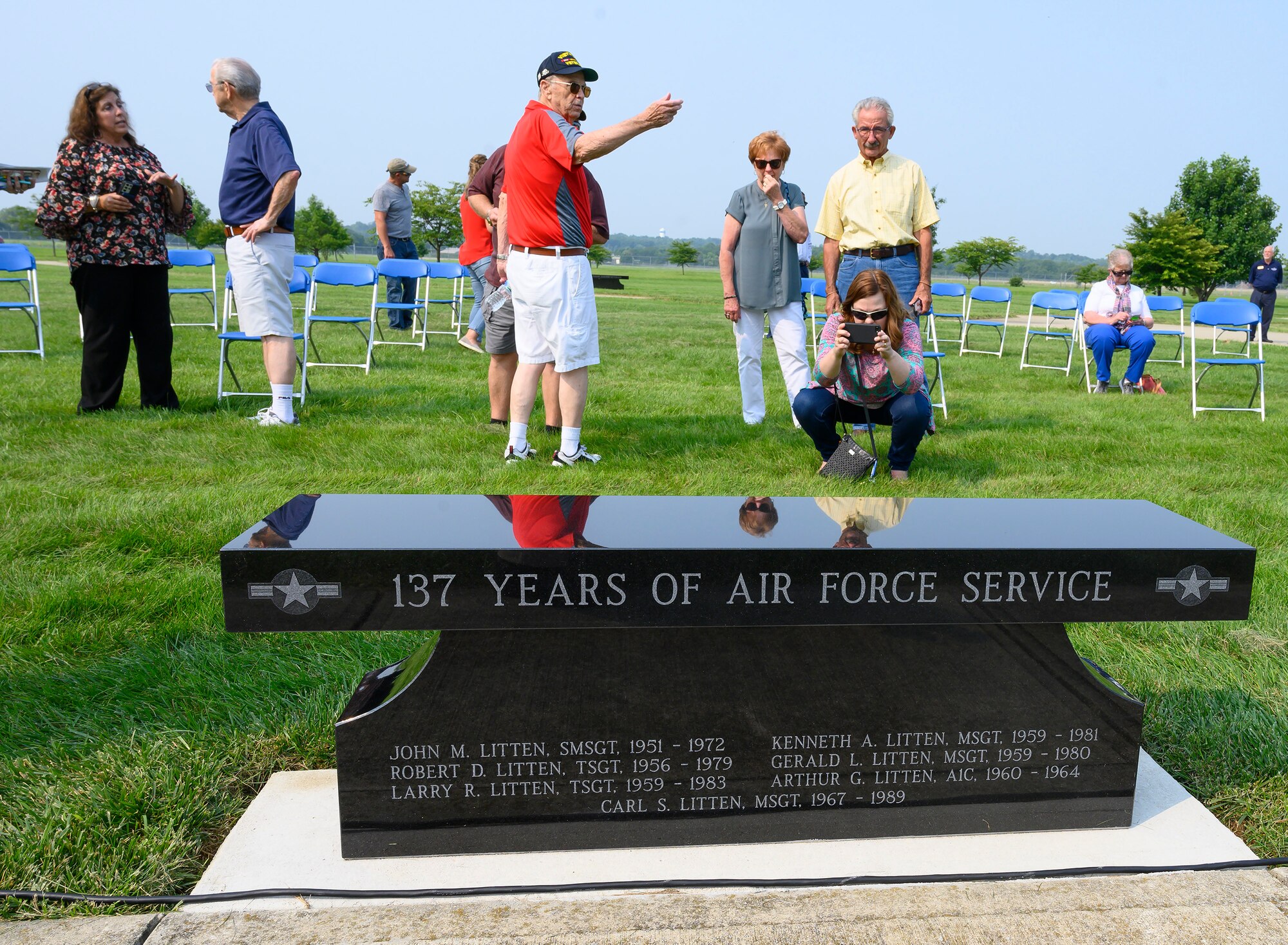 Attendees of a dedication ceremony at the National Museum of the Air Force, Wright-Patterson Air Force Base, Ohio, July 20, 2021, look at a new memorial bench honoring one family of brothers for their service. The seven Litten brothers served a combined total of 137 years in the U.S. Air Force. (U.S. Air Force photo by R.J. Oriez)