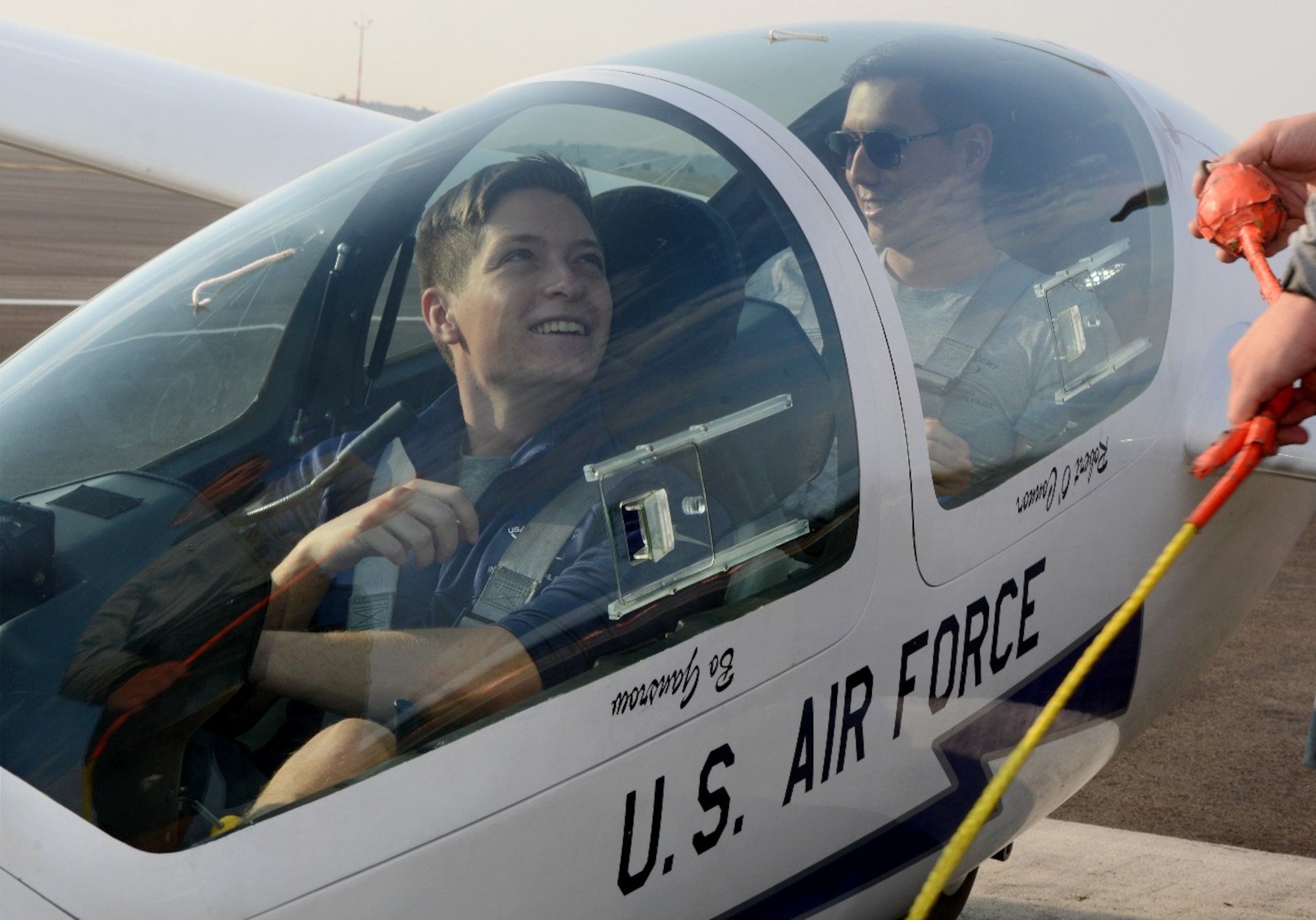 Second Lt. Spencer Brown, a 2021 graduate of the U.S. Air Force Academy and Capt. Brandon Leet, assigned to the 306th Flying Training Squadron, watch as their glider is hook to a tow plane.