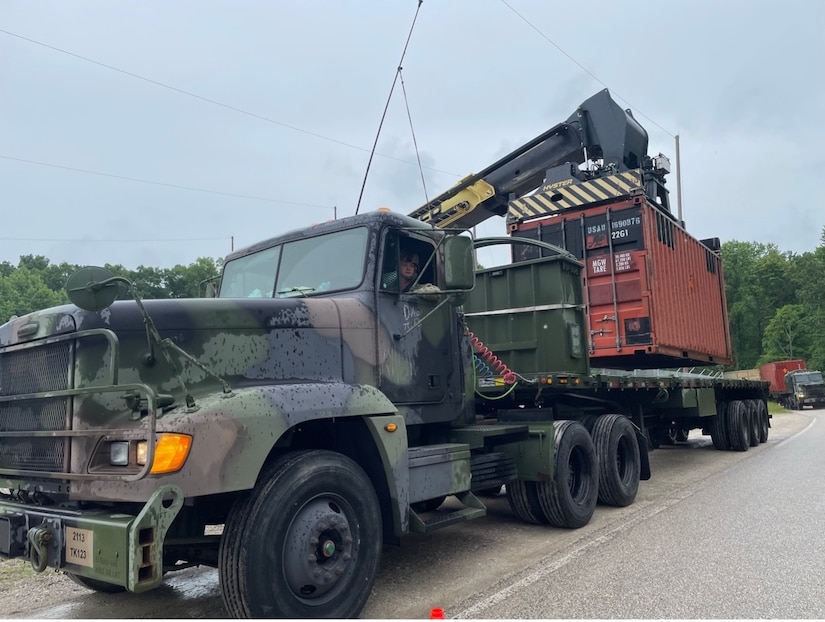 Moving equipment places a cargo container on a truck.