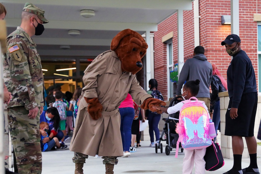 McGruff the Crime Dog greets a little girl as she enters a school.