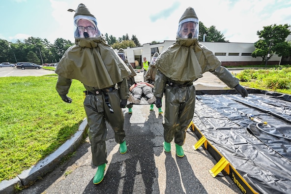 66th Medical Squadron In-Place Patient Decontamination Team members Senior Airmen Gavin Fluery and Ezekiel Grogan, carry an injured role player, Staff Sgt. Leilanie Kenley, 66th Security Forces Squadron NCO in charge of commander support staff, to a decontamination tent during a Ready Eagle exercise at Hanscom Air Force Base, Mass., July 30. The disaster response exercise prepared MDS staff to respond to chemical, biological, radiological, nuclear, or explosive incidents. (U.S. Air Force photo by Todd Maki)